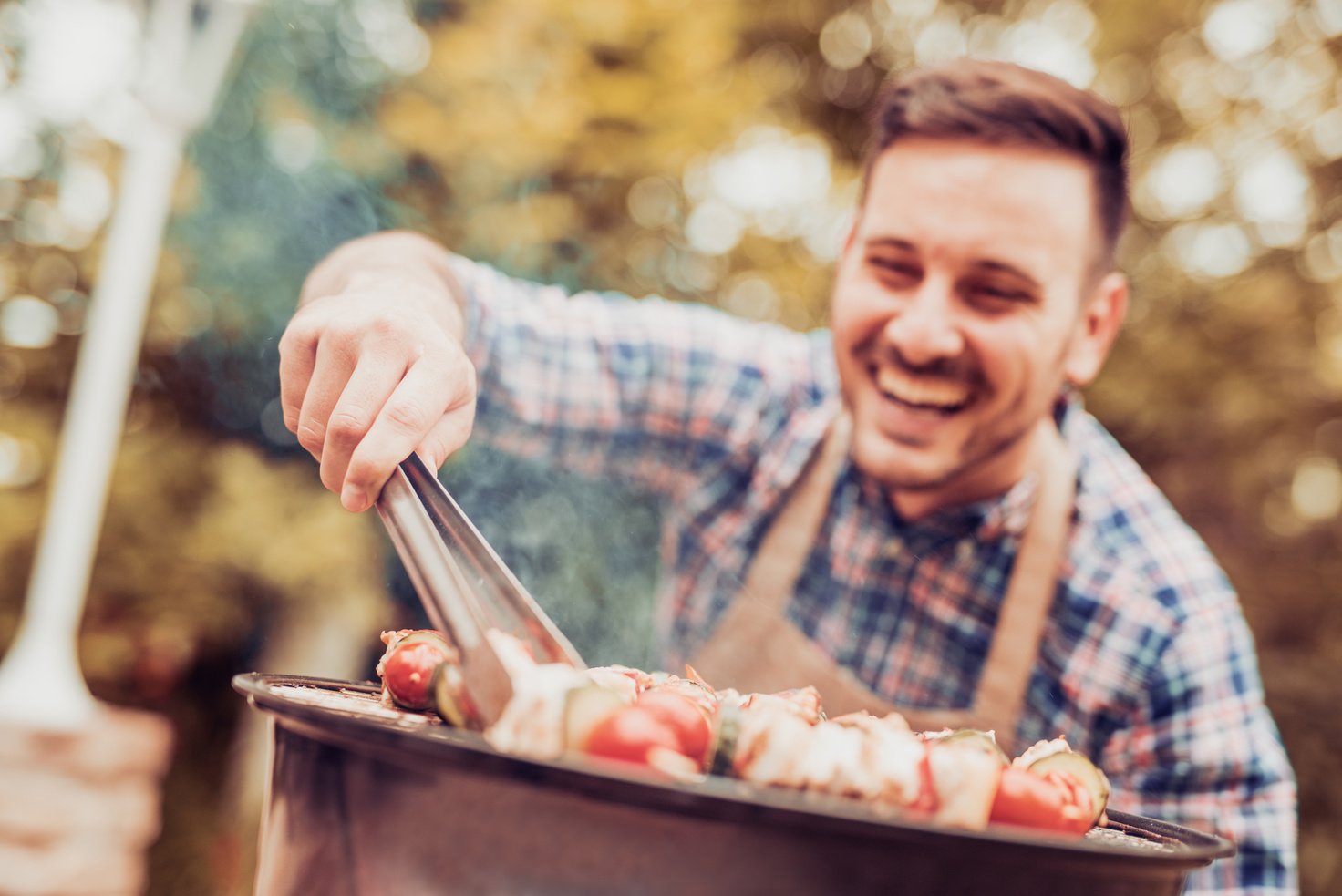 Young man preparing barbecue outdoors.